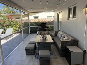 An outdoor patio with a wooden table, cushioned seating, and string lights.