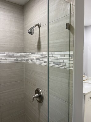 Een bad/douchecombinatie, handdoeken, zeep, shampoo