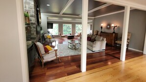 A spacious living room with hardwood floors, a stone fireplace, and a large window providing natural light.