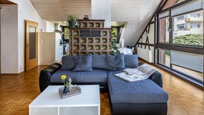 Una sala de estar moderna con un sofá seccional, una mesa de centro y un ventanal con vista a edificios.