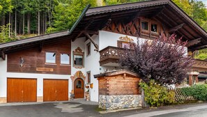 A traditional wooden house with a stone foundation, wooden balconies, and a wooden door. - Apartment 'Kleisl' with Mountain View, Garden & Wi-Fi (Grainau)