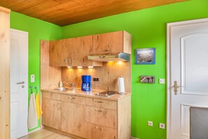A kitchen with wooden cabinets, a coffee maker, and a sink. - Apartment 'Kleisl' with Mountain View, Garden & Wi-Fi (Grainau)