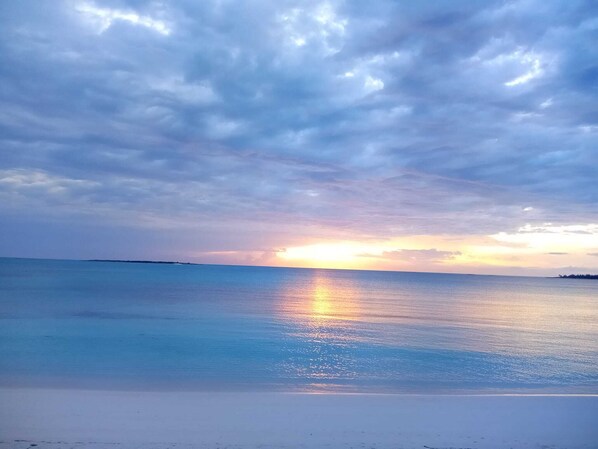 A beach with a sunset over the ocean. - 960 Sq. ft Beach Front Villa located in Steventon, Exuma, Bahamas . (Steventon)