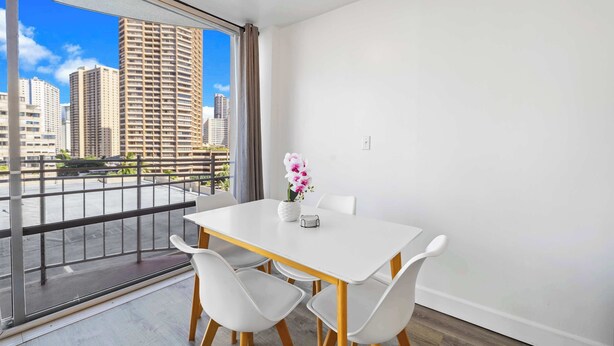 A modern room with a balcony, a white table, and two chairs. - Prime Waikiki Studio – Walk to the Beach! (Honolulu)