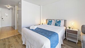 A hotel room with a bed, bedside table, and a chair. - Prime Waikiki Studio – Walk to the Beach! (Honolulu)