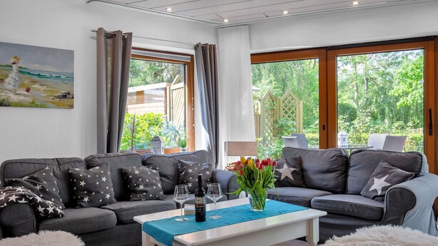 A modern living room with a grey sofa set, a white coffee table, and a painting on the wall. - Beautiful private villa for 20 people with WIFI, TV, terrace and pets allowed (Bremerhaven)