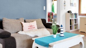 A living room with a sofa, a coffee table, and a bookshelf. - Beautiful private villa for 20 people with WIFI, TV, terrace and pets allowed (Bremerhaven)