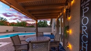Un patio couvert avec une piscine, des meubles en osier et une pancarte sur laquelle on peut lire : « Bienvenue sur notre PORCHE ».