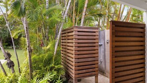 Una estructura de madera con listones horizontales, rodeada de exuberante vegetación tropical.