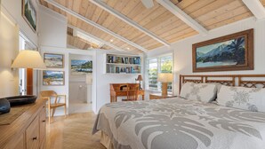 Un dormitorio con una cama grande, vigas de madera en el techo, una estantería y un escritorio con una silla.