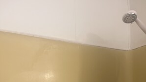 A corner of a room with a white ceiling and a beige wall. There is a showerhead visible on the wall. - BK to JAX CITY GIRL —-> COUNTRY GIRL (Jacksonville)