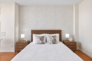 A bedroom with a large bed, two nightstands, and a textured wall.