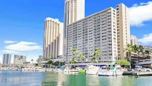 A waterfront hotel with multiple high-rise buildings, a marina with boats, and palm trees. - Waikiki Escape – Perfect Location, Near the Beach! (Honolulu)
