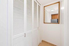 A hallway with white louvered closets and a mirror on the wall. - Waikiki Escape – Perfect Location, Near the Beach! (Honolulu)
