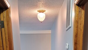 A hallway with wooden flooring, a ceiling light fixture, and a radiator on the wall.