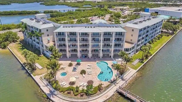 A hotel with a central courtyard featuring a swimming pool, surrounded by palm trees and lounge chairs.