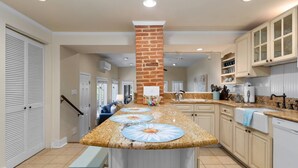 A spacious kitchen with a central island, built-in cabinets, and a brick accent wall. - Historic Happy Home Steps from Main Street w Private Yard, Screened-In Porch & Parking (Annapolis)
