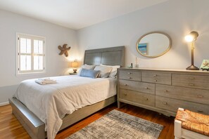 A bedroom with a bed, a dresser, a round mirror, and a window with shutters. - Gather, Relax & Explore — Townhome 1 Block from State Capitol Building with Backyard & Parking (Annapolis)