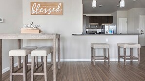 A modern kitchen with a central island, bar stools, and a welcome sign. - Monthly Stays Luxe Des Peres Suite with Complimentary Starbucks Onsite!  (Des Peres)