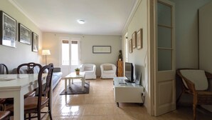 Un salon comprenant une table à manger, des chaises, un canapé, un téléviseur et une bibliothèque.