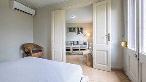 Une chambre à coucher avec un lit, une chaise en osier, un canapé et une lampe dans un couloir.