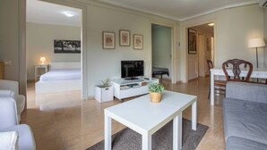 Une chambre d’hôtel moderne avec un lit, une télévision, une table blanche et un canapé.