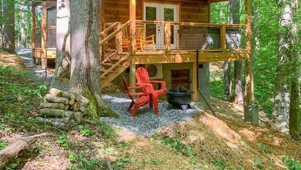 Une cabane avec une façade en bois, une véranda et un escalier menant à l’entrée.