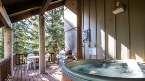 Une terrasse en bois avec un jacuzzi, un coin salon extérieur et un barbecue.