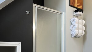 Un bany modern amb dutxa de vidre, vàter i barra per a tovalloles.