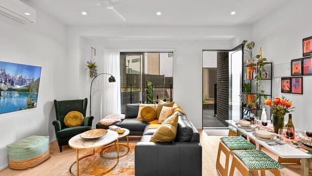 A modern living room with a sofa, coffee table, and dining area. - StayCentral - Boulevard Gardens (Coburg)