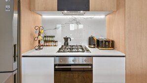 A kitchen with a stainless steel refrigerator, a gas stove, and wooden cabinets. - StayCentral - Boulevard Gardens (Coburg)