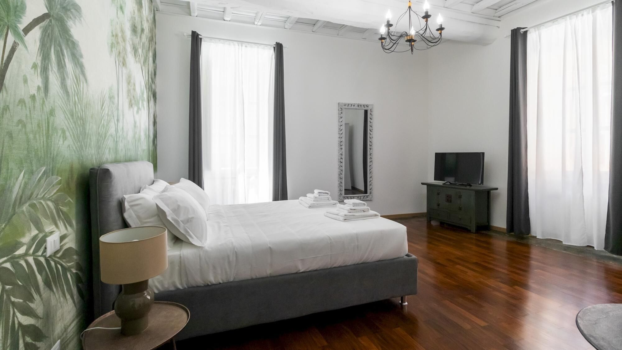 A bedroom with a bed, a television on a cabinet, and a chandelier.