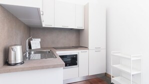 Una cocina moderna con armarios blancos, un lavamanos de acero inoxidable, una tetera y un horno empotrado.