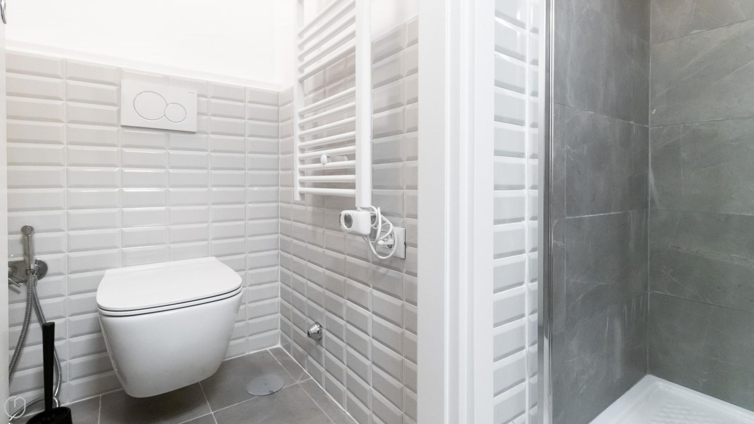 Ein modernes Badezimmer mit Toilette, Dusche und gefliesten Wänden.