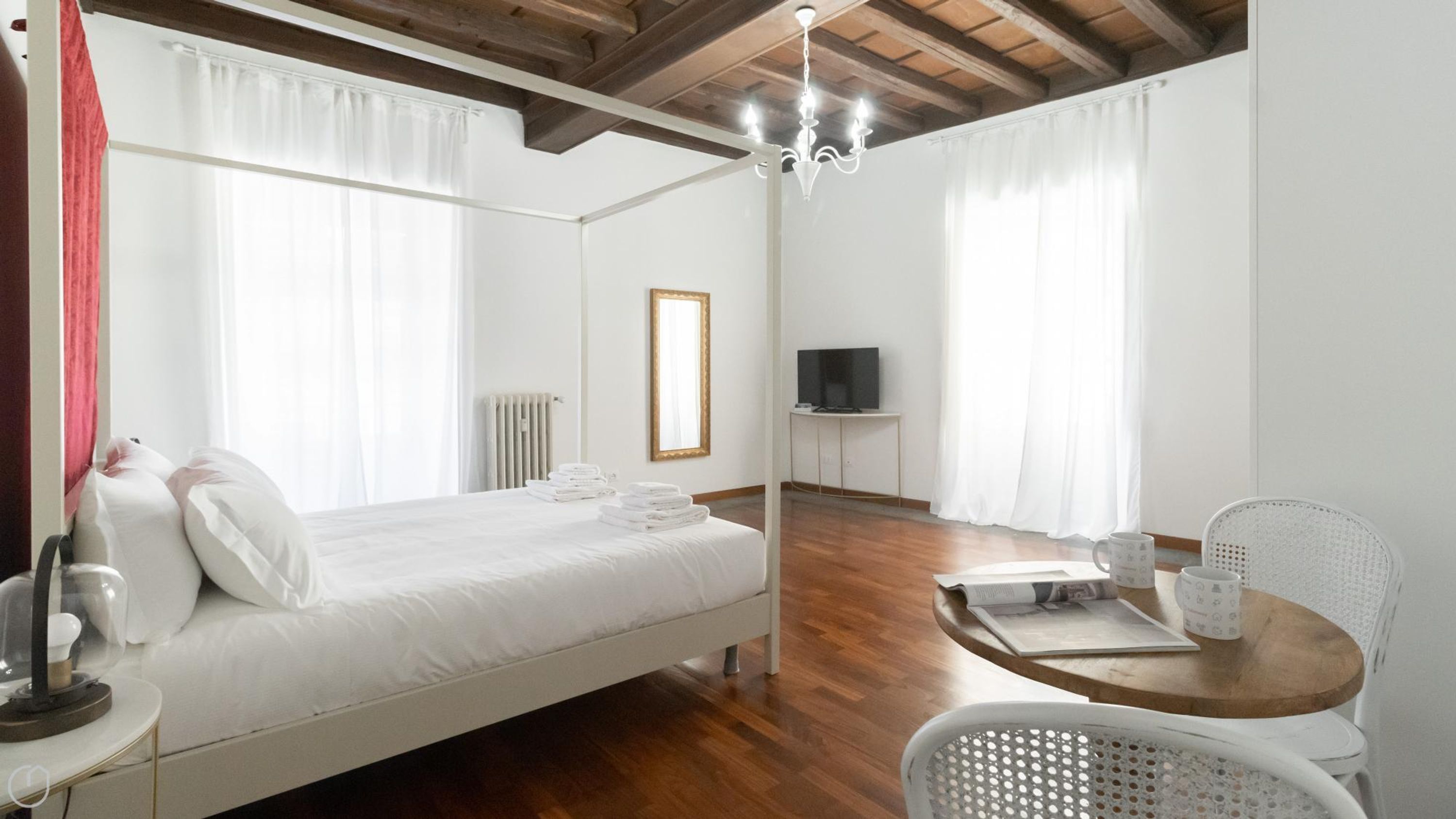 A bedroom with a bed, a bedside table, a chair, a TV, and a radiator.