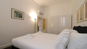 A hotel room with a neatly made bed, a framed picture on the wall, and a wardrobe. - Italianway Easy - Vanvitelli 49 (Milan)