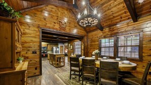 A wooden interior with a dining area, kitchen, and a chandelier. - Bent Pine Lodge | Spacious 4BR Broken Bow Cabin with Hot Tub, Fire Pit & Grill (Hochatown)