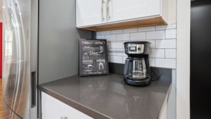 A kitchen with a coffee maker, a coffee grinder, and a refrigerator. - Townley on 6th! (Phoenix)