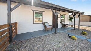 A building with a covered patio area, a wooden bench, a wicker chair, and a potted plant. - Townley on 6th! (Phoenix)