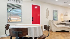 A dining area with a table set for four, a red door, and a white wall with a 'THANKFUL' sign. - Townley on 6th! (Phoenix)