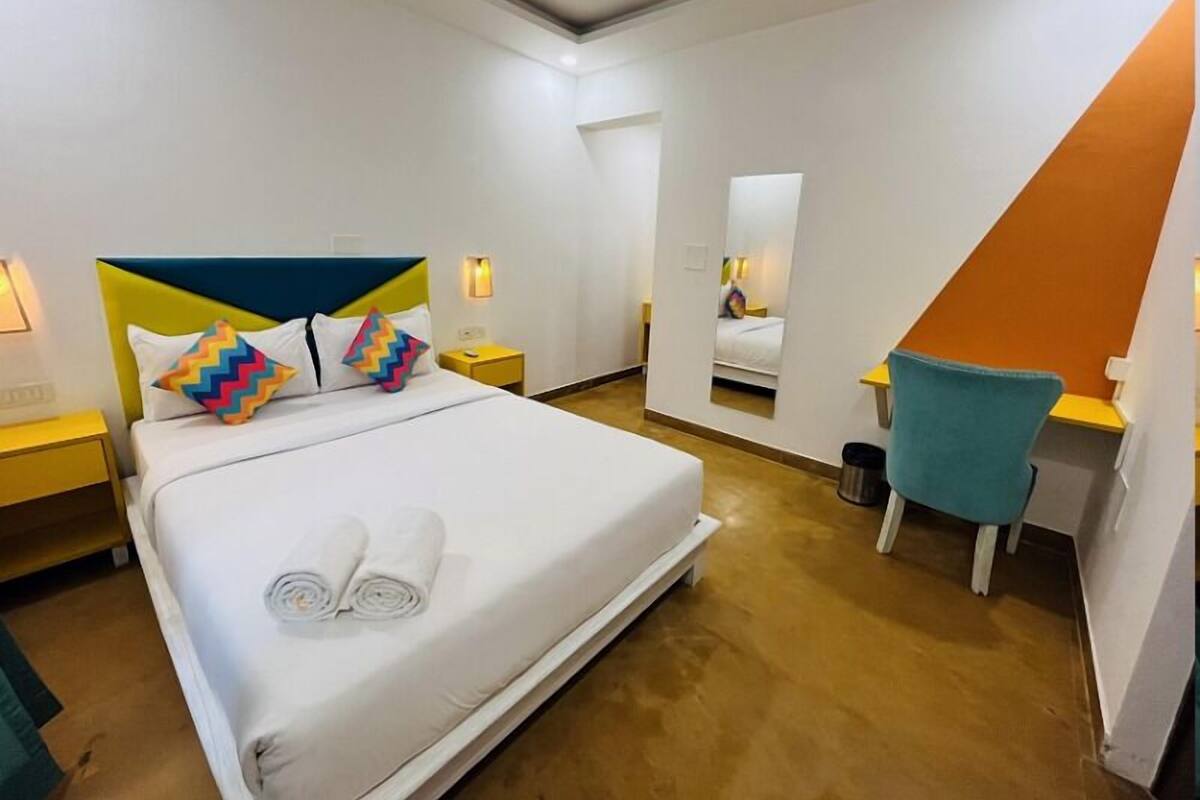 A hotel room with a bed, a desk, and a chair.
