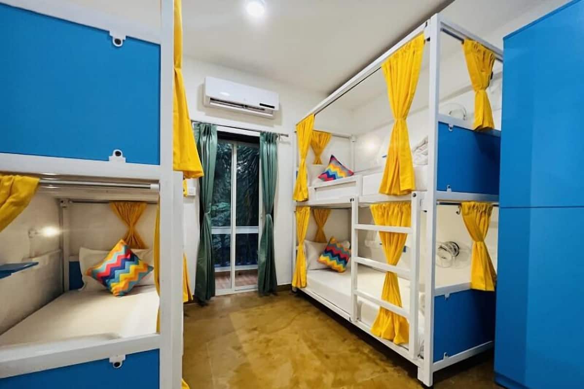 A room with bunk beds, yellow curtains, and an air conditioning unit.