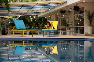 A pool area with two sun loungers, a covered seating area, and a glass-enclosed pool.