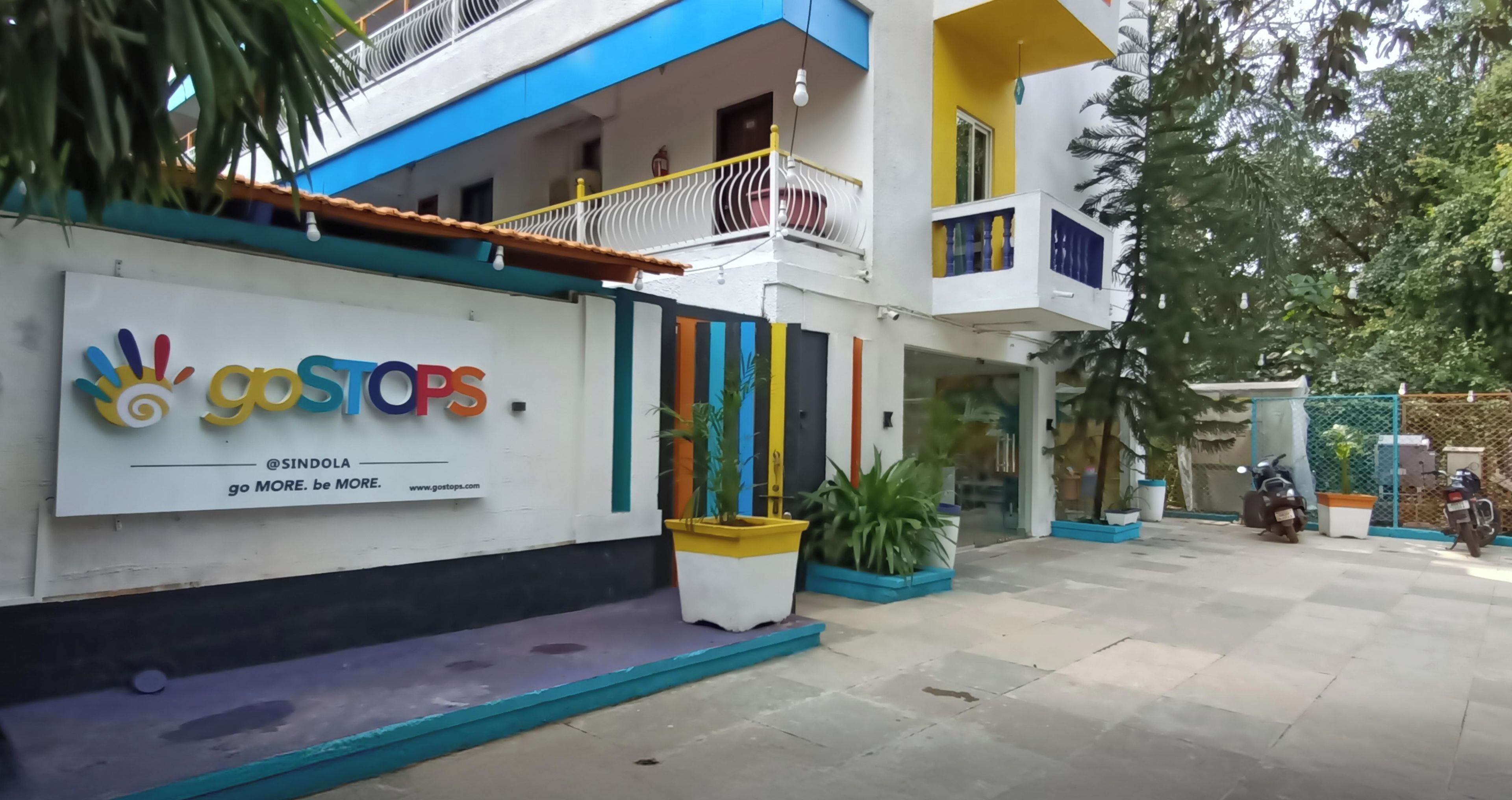 Un edificio con fachada colorida, un letrero que dice 'goSTOPS', y un texto que indica 'Ubicado justo en el corazón de la ciudad'.