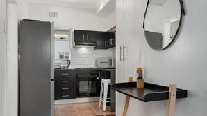 Eine moderne Küche mit schwarzen Schränken, einem weißen Kühlschrank und einer schwarzen Arbeitsplatte.