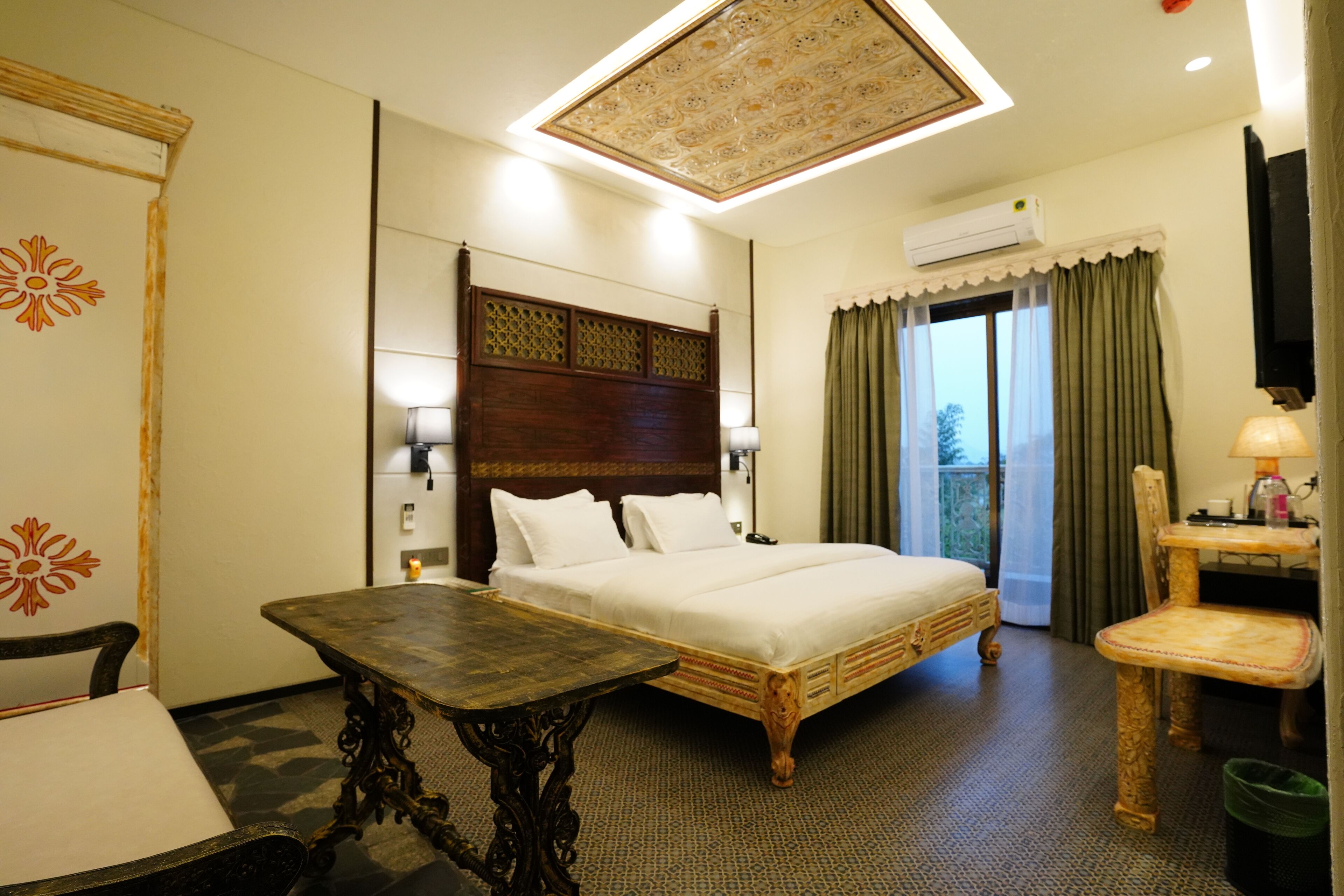 Una habitación de hotel con una cama grande, una mesa de madera, una silla, un escritorio y un televisor.