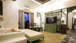A hotel room with a bed, a television, a table, and a chair. - The Kinara Village (Mawal)
