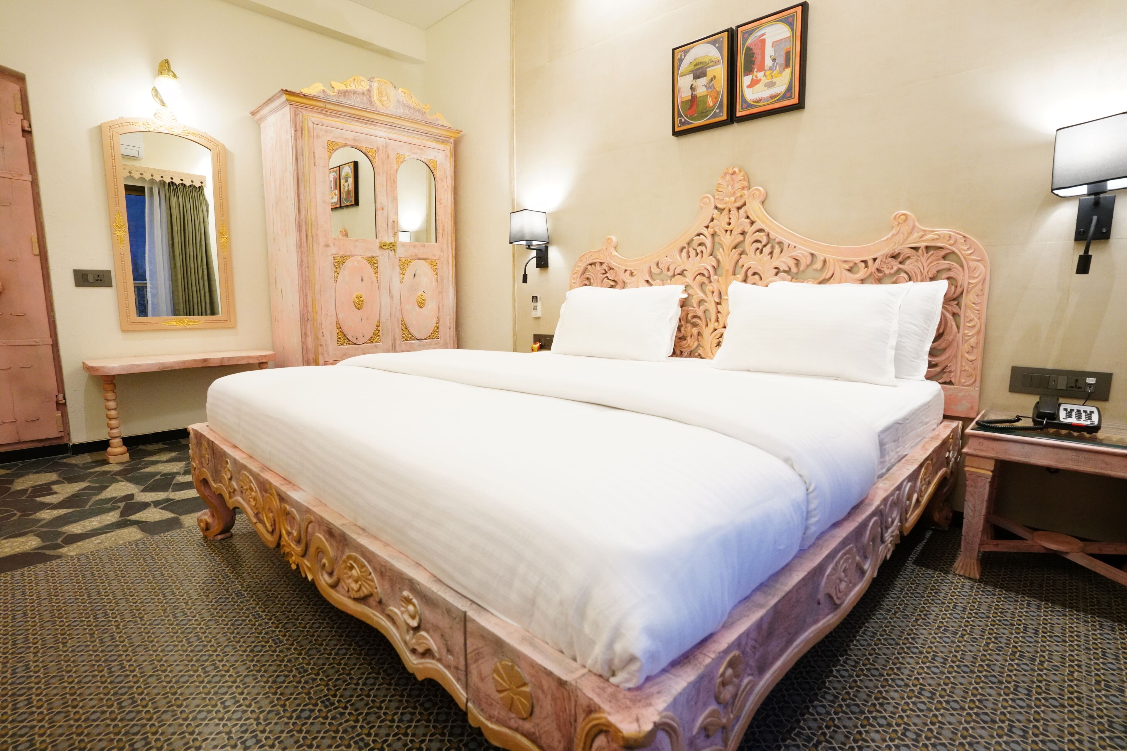 A spacious bedroom with a large bed, a wooden wardrobe, a bedside table, and a wall-mounted lamp.