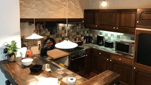Cocina con armarios de madera, estufa, microondas y cafetera.