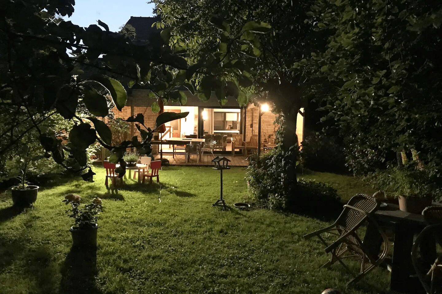 A backyard with a patio area, outdoor furniture, and potted plants.
